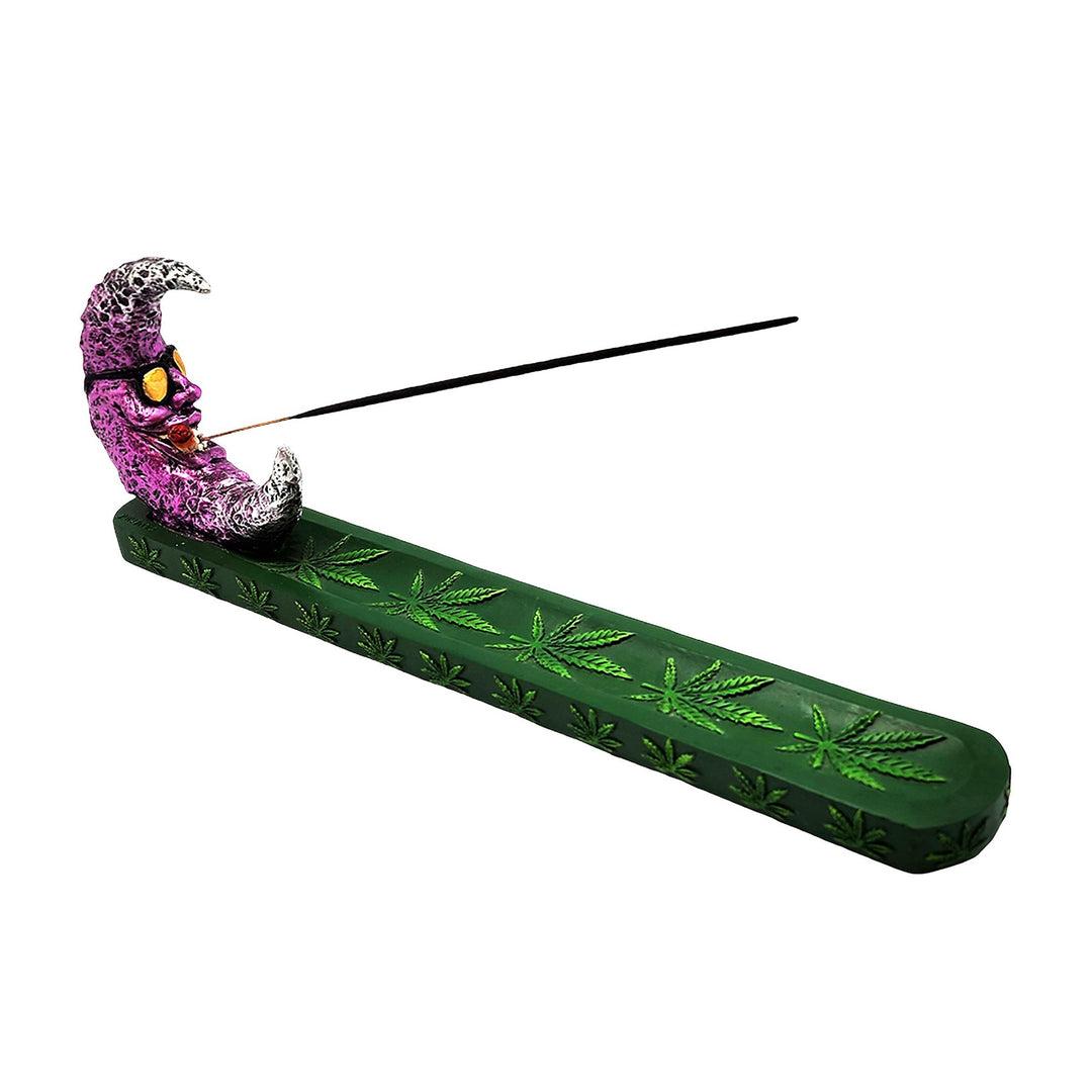 Green leaf-patterned incense holder with a glittery crescent moon figure and a black incense stick.